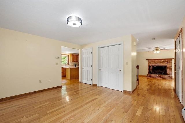 71 Johnny Appleseed Ln, Leominster, MA 01453 - unfurnished living room with light wood-style flooring, a ceiling fan, a fireplace, and baseboards