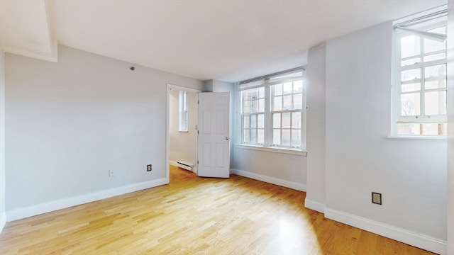 unfurnished bedroom with baseboard heating, light wood-type flooring, and multiple windows