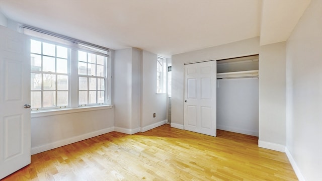 unfurnished bedroom with a closet, multiple windows, and light hardwood / wood-style flooring