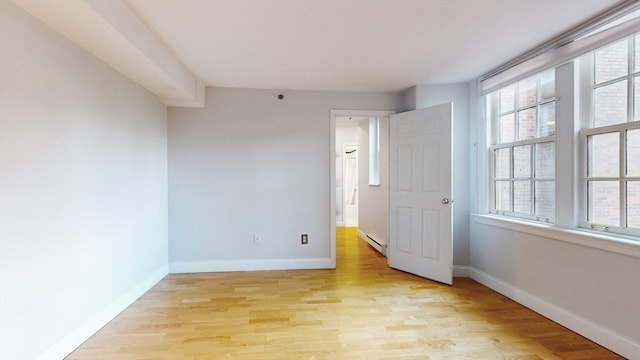 unfurnished bedroom with light wood-type flooring, a baseboard radiator, and multiple windows