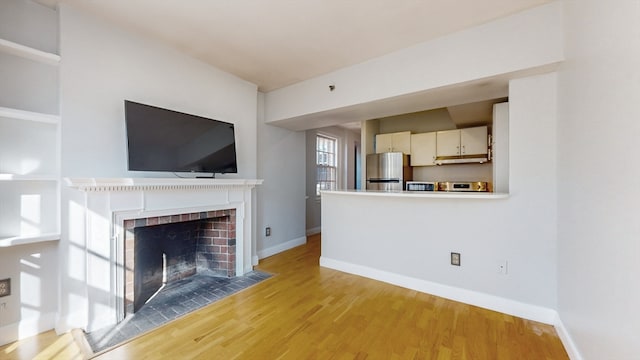 unfurnished living room with light wood-type flooring and a brick fireplace