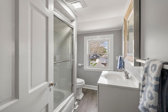 bathroom featuring toilet, vanity, wood finished floors, crown molding, and baseboards