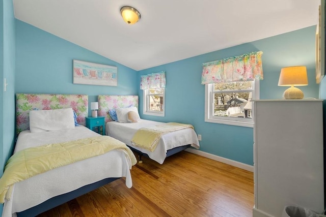 bedroom with wood finished floors, lofted ceiling, and baseboards