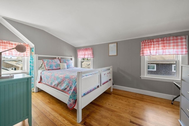bedroom with light wood-style floors, lofted ceiling, and baseboards