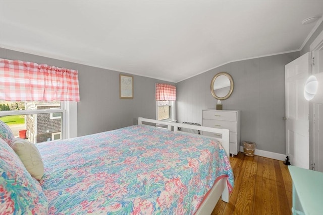 bedroom featuring multiple windows, wood finished floors, ornamental molding, lofted ceiling, and baseboards