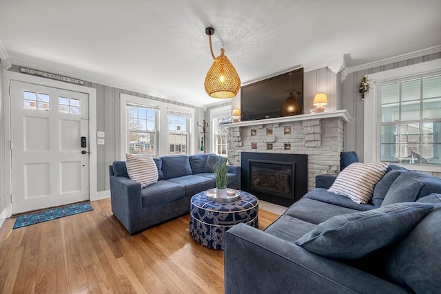living area featuring crown molding, a fireplace, healthy amount of natural light, and light wood-type flooring