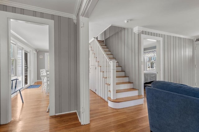 staircase featuring ornamental molding and wood finished floors