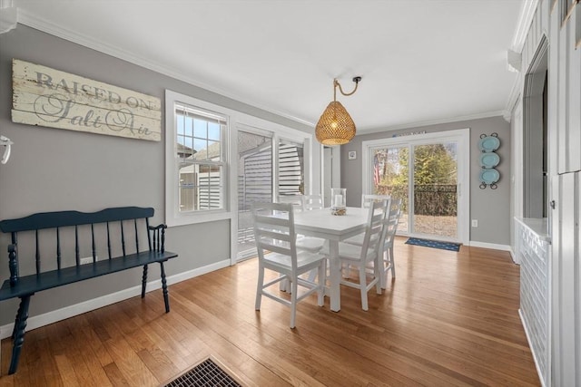 dining room with ornamental molding, wood finished floors, plenty of natural light, and baseboards