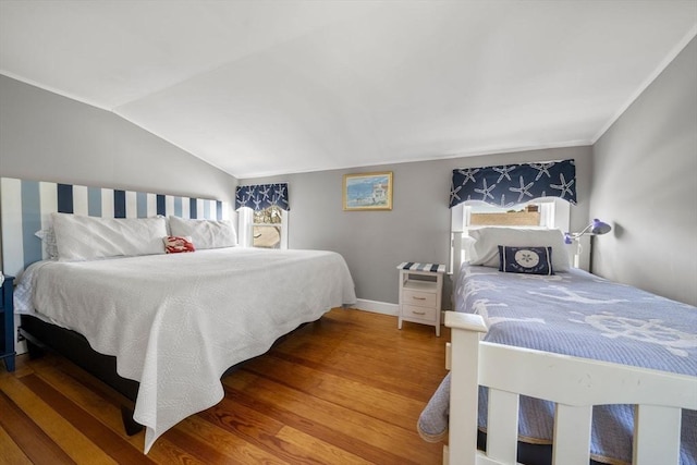 bedroom with wood finished floors, vaulted ceiling, and baseboards