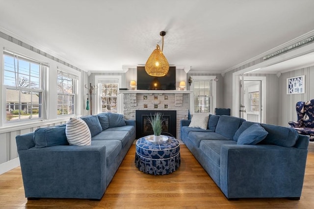 living room featuring crown molding, healthy amount of natural light, a fireplace, and wood finished floors