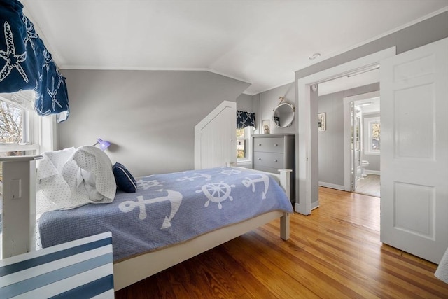 bedroom with wood finished floors, baseboards, ornamental molding, and vaulted ceiling