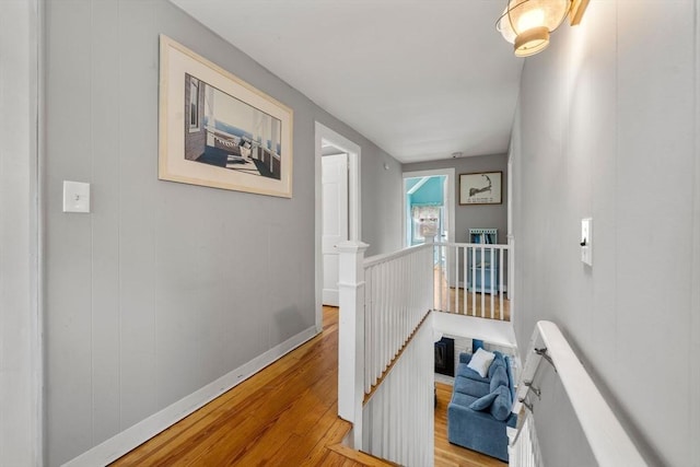 hall with an upstairs landing, wood finished floors, and baseboards