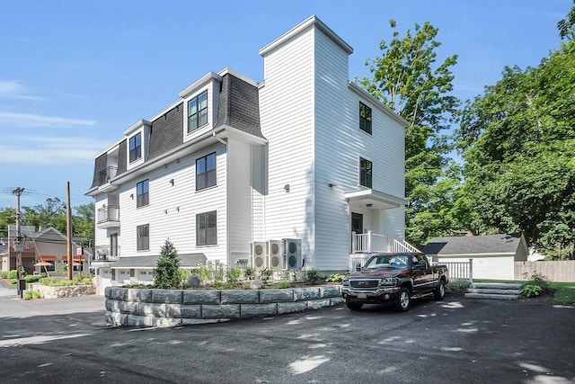 50 Main St Unit 101, Pepperell, MA 01463 - view of property exterior with mansard roof, a shingled roof, and driveway