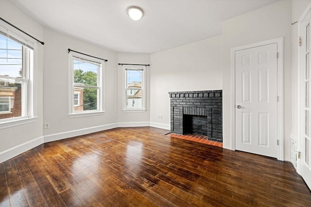 unfurnished living room featuring a brick fireplace and dark hardwood / wood-style floors