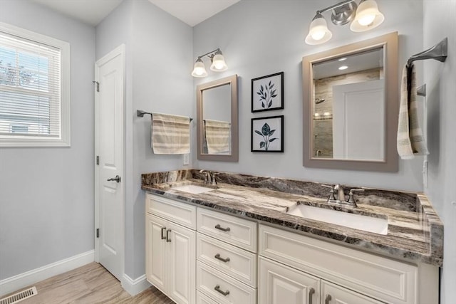 10 Brickett Ave, Haverhill, MA 01830 - full bath featuring wood finished floors, baseboards, double vanity, and tiled shower