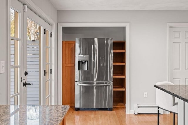 kitchen featuring baseboard heating, stainless steel fridge with ice dispenser, light wood-style floors, and stone counters