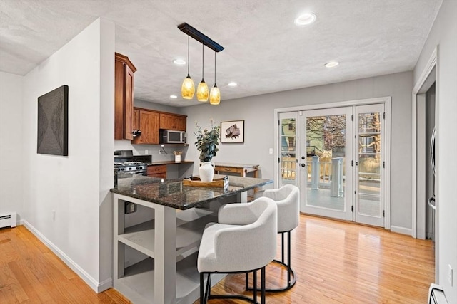 kitchen with light wood finished floors, brown cabinets, appliances with stainless steel finishes, and a baseboard heating unit