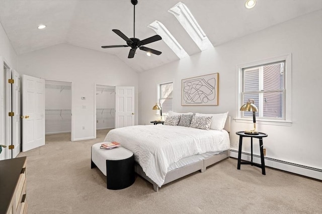 bedroom with a ceiling fan, a baseboard radiator, vaulted ceiling with skylight, recessed lighting, and light carpet