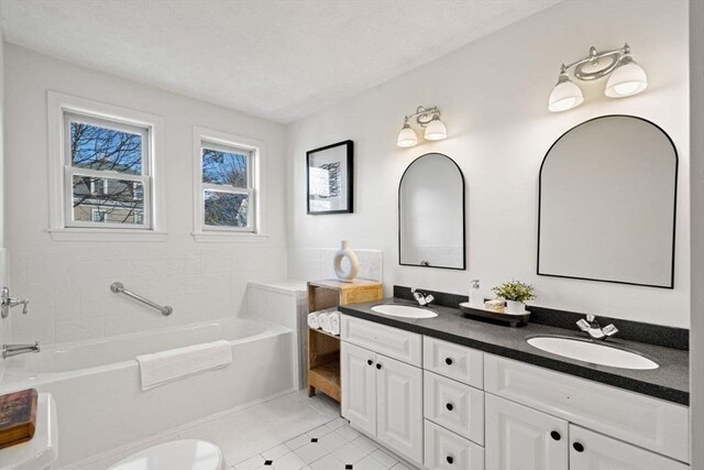 bathroom featuring tile patterned floors, a garden tub, double vanity, and a sink