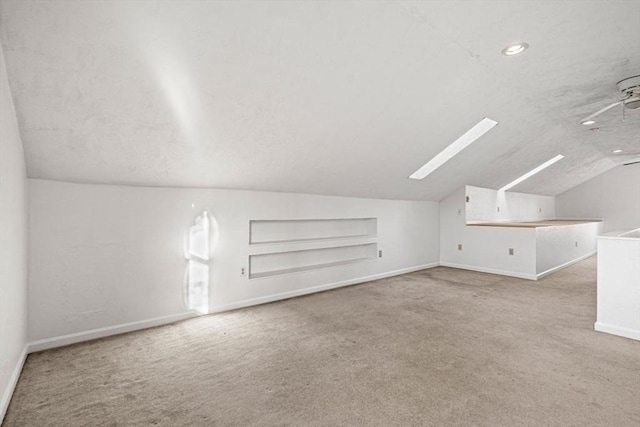 bonus room featuring baseboards, built in shelves, lofted ceiling with skylight, and carpet flooring