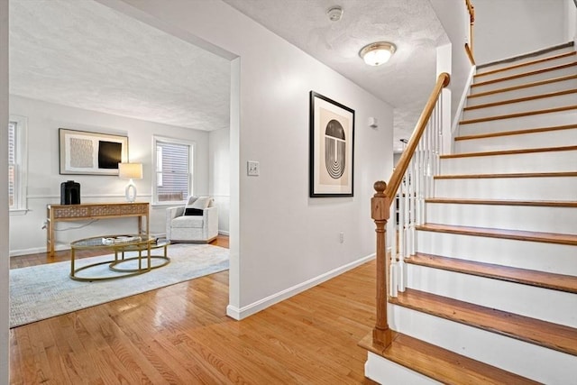 stairway with baseboards, a textured ceiling, and wood finished floors