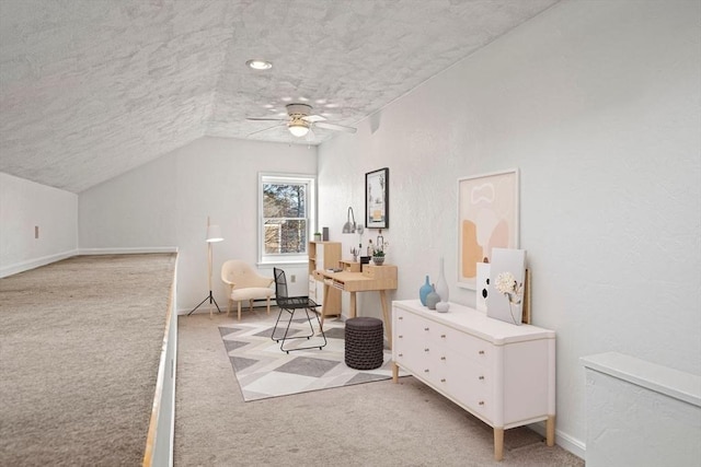 office area featuring lofted ceiling, ceiling fan, a textured ceiling, light carpet, and a textured wall