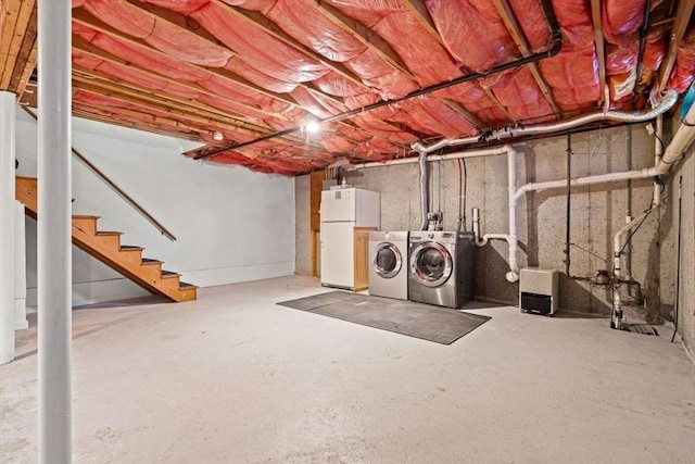 unfinished basement featuring stairs, independent washer and dryer, and freestanding refrigerator