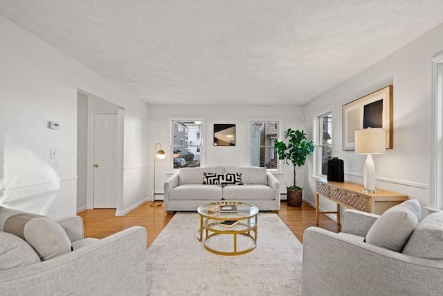 living room with a baseboard radiator, baseboards, and wood finished floors