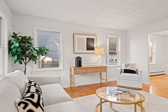 living room featuring a baseboard heating unit, baseboards, and wood finished floors