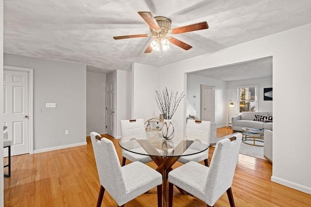 dining space with baseboards, a textured ceiling, a ceiling fan, and light wood finished floors