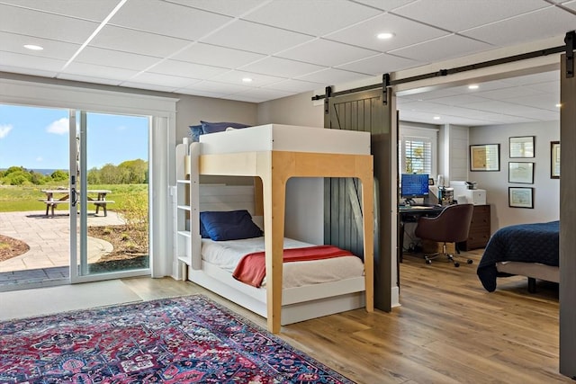 27 Gully Ln, Sandwich, MA 02537 - bedroom with a barn door, access to exterior, light wood-type flooring, multiple windows, and a drop ceiling