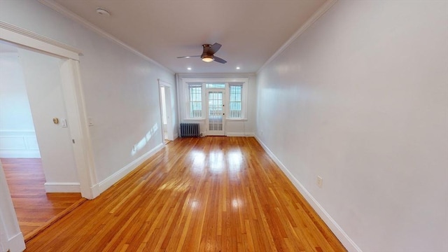 empty room featuring ceiling fan, crown molding, radiator, and light hardwood / wood-style flooring