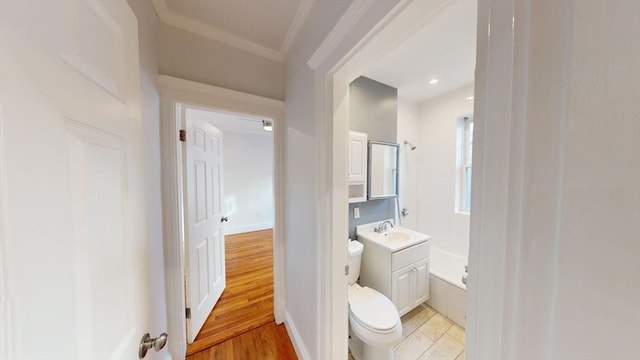 bathroom with a bathtub, vanity, crown molding, hardwood / wood-style floors, and toilet