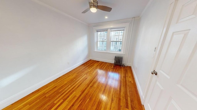 spare room featuring light hardwood / wood-style flooring, radiator, ornamental molding, and ceiling fan