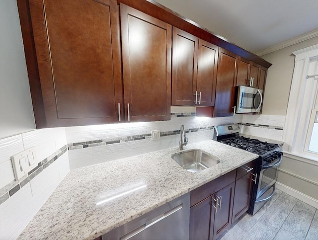 kitchen featuring sink, light hardwood / wood-style flooring, ornamental molding, appliances with stainless steel finishes, and light stone counters