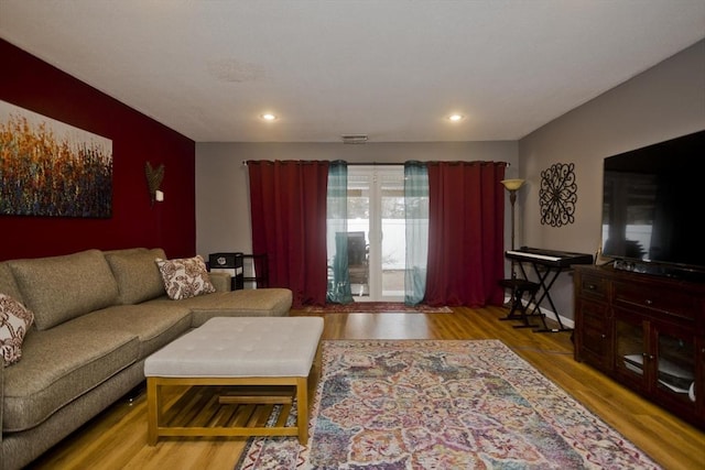 living area with baseboards, wood finished floors, visible vents, and recessed lighting