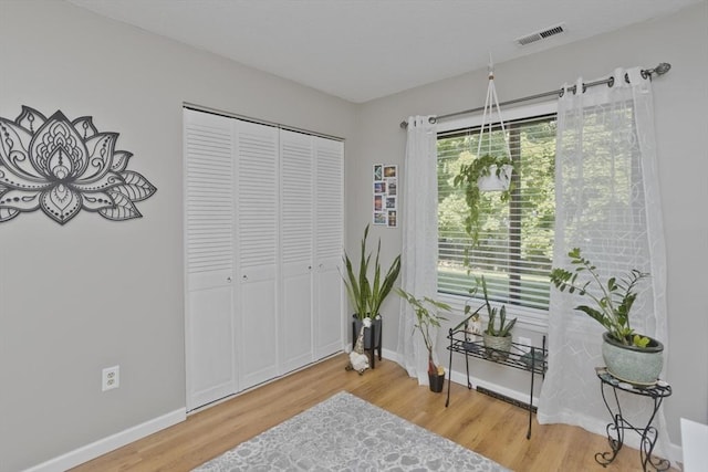 living area featuring visible vents, baseboards, and wood finished floors