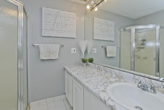 bathroom with a stall shower, tile patterned flooring, vanity, and baseboards