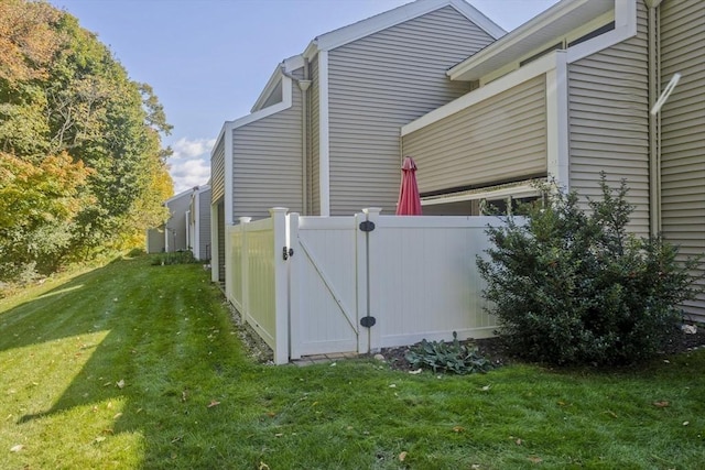 view of property exterior featuring a lawn, fence, and a gate