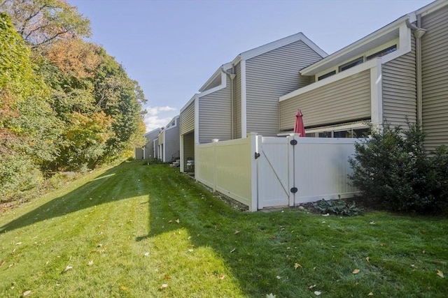 view of side of property featuring a lawn, fence, and a gate