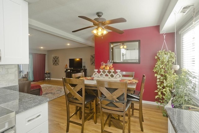 dining room with light wood finished floors, beam ceiling, visible vents, and baseboards