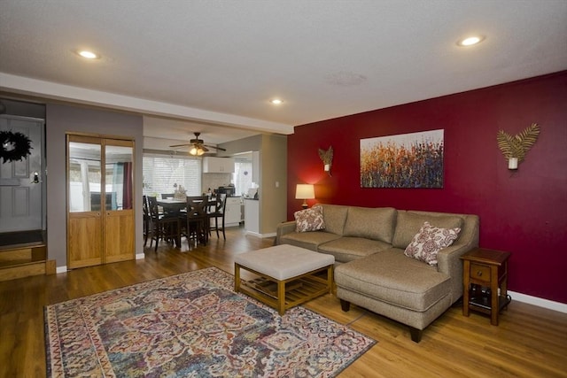 living area with an accent wall, recessed lighting, wood finished floors, and baseboards