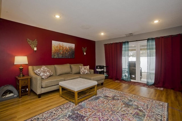 living area with wood finished floors, visible vents, and recessed lighting