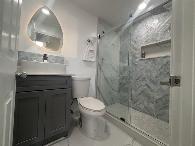 full bath featuring toilet, marble finish floor, a marble finish shower, and vanity