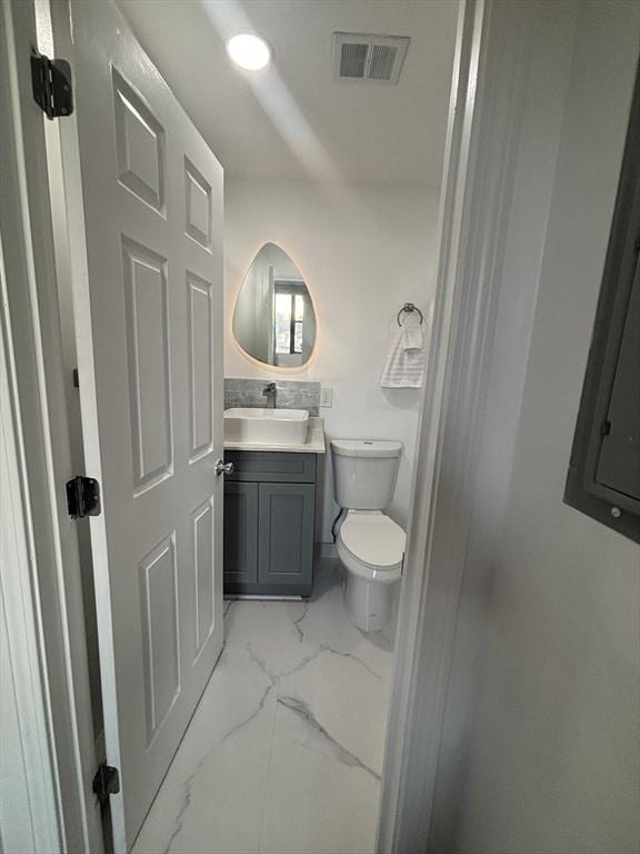 bathroom featuring marble finish floor, visible vents, vanity, and toilet