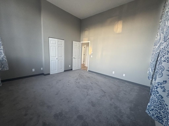 unfurnished bedroom featuring a high ceiling, carpet flooring, and baseboards