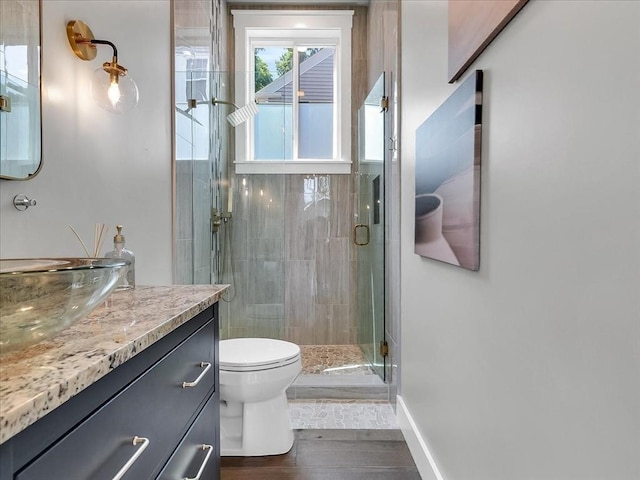 bathroom featuring a stall shower, baseboards, vanity, and toilet