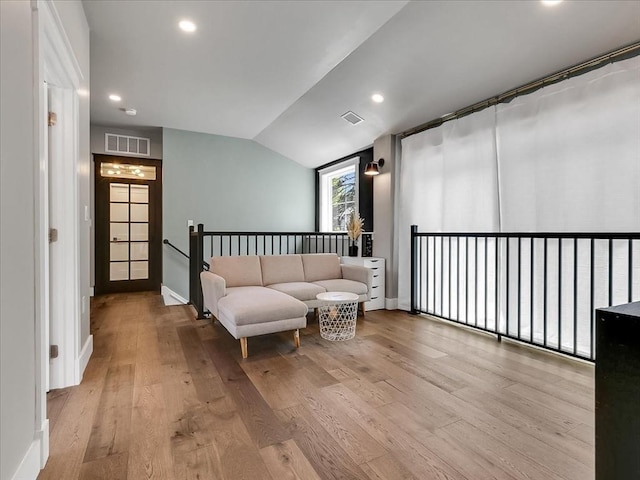 living area featuring vaulted ceiling, light wood-style flooring, visible vents, and recessed lighting