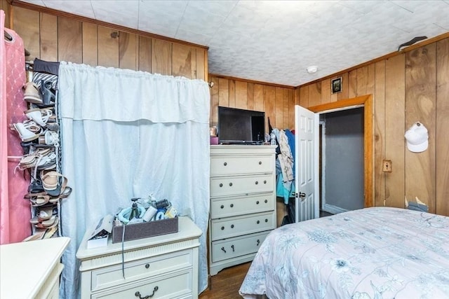 bedroom with dark wood finished floors and wooden walls