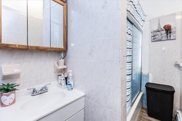 bathroom with bath / shower combo with glass door, tile walls, and vanity